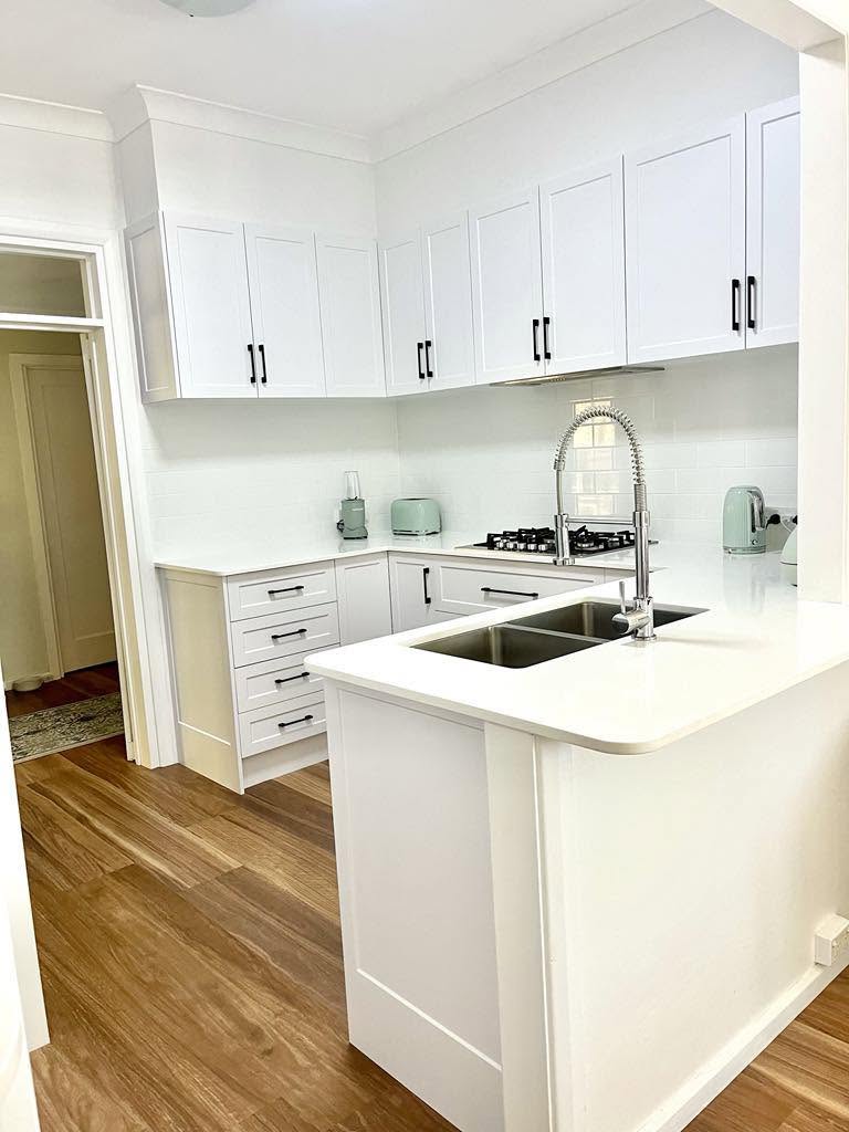 White shaker kitchen with island bench and gas cooktop